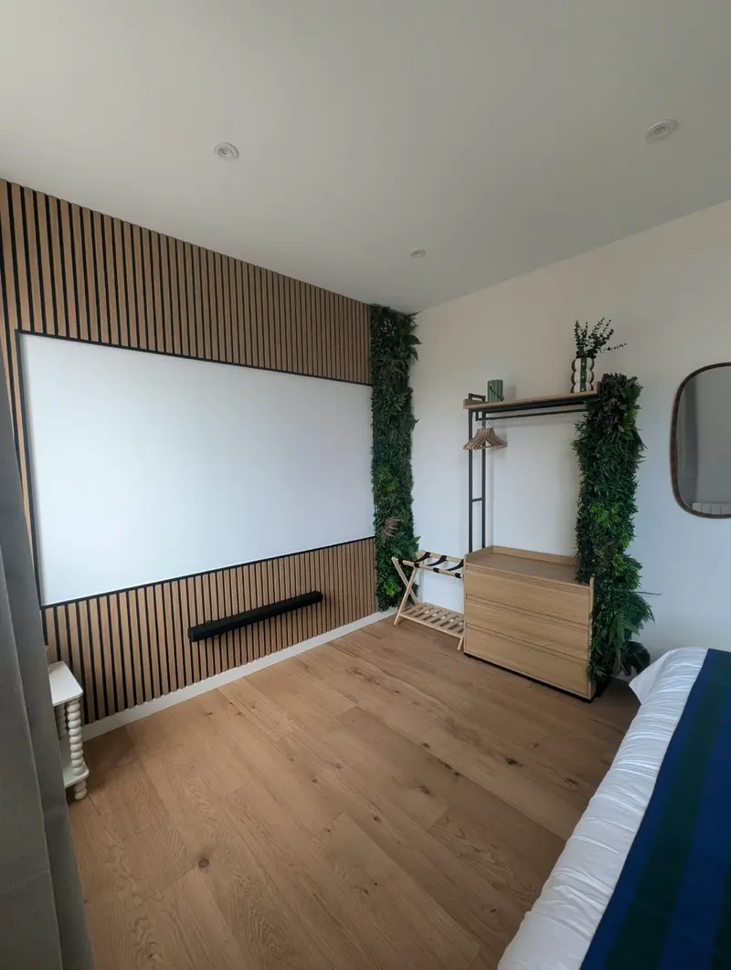 Pièce lumineuse et épurée : parquet clair, mur à tasseaux de bois et plantes vertes